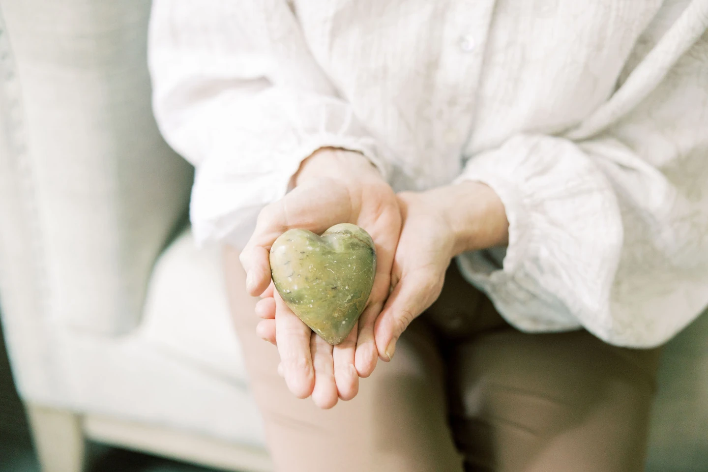 Woman's hand holding a heart shaped rock