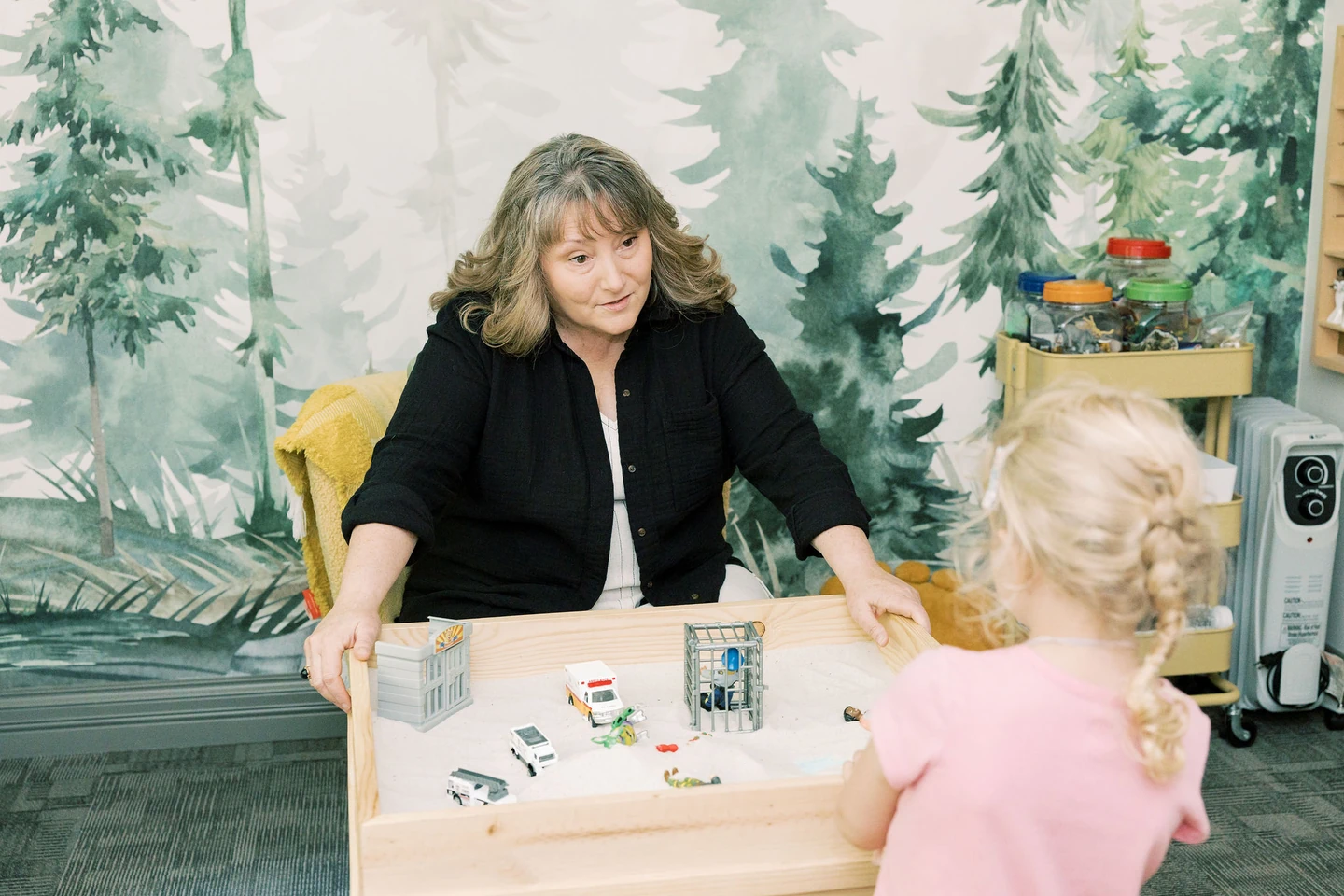 Therapist sitting at table working with child during play therapy session