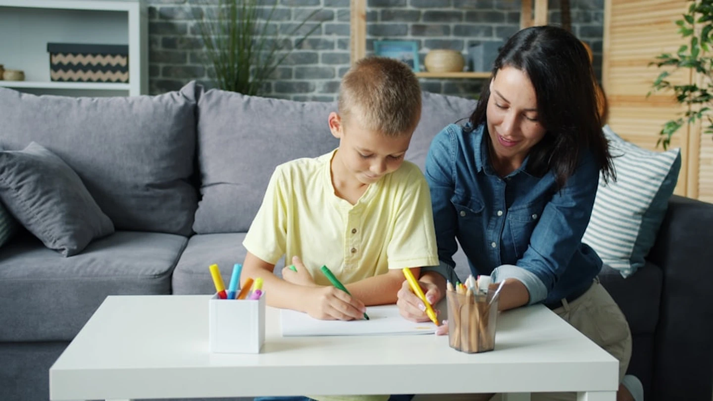 Family therapist sitting next to child, drawing a picture, during family therapy session